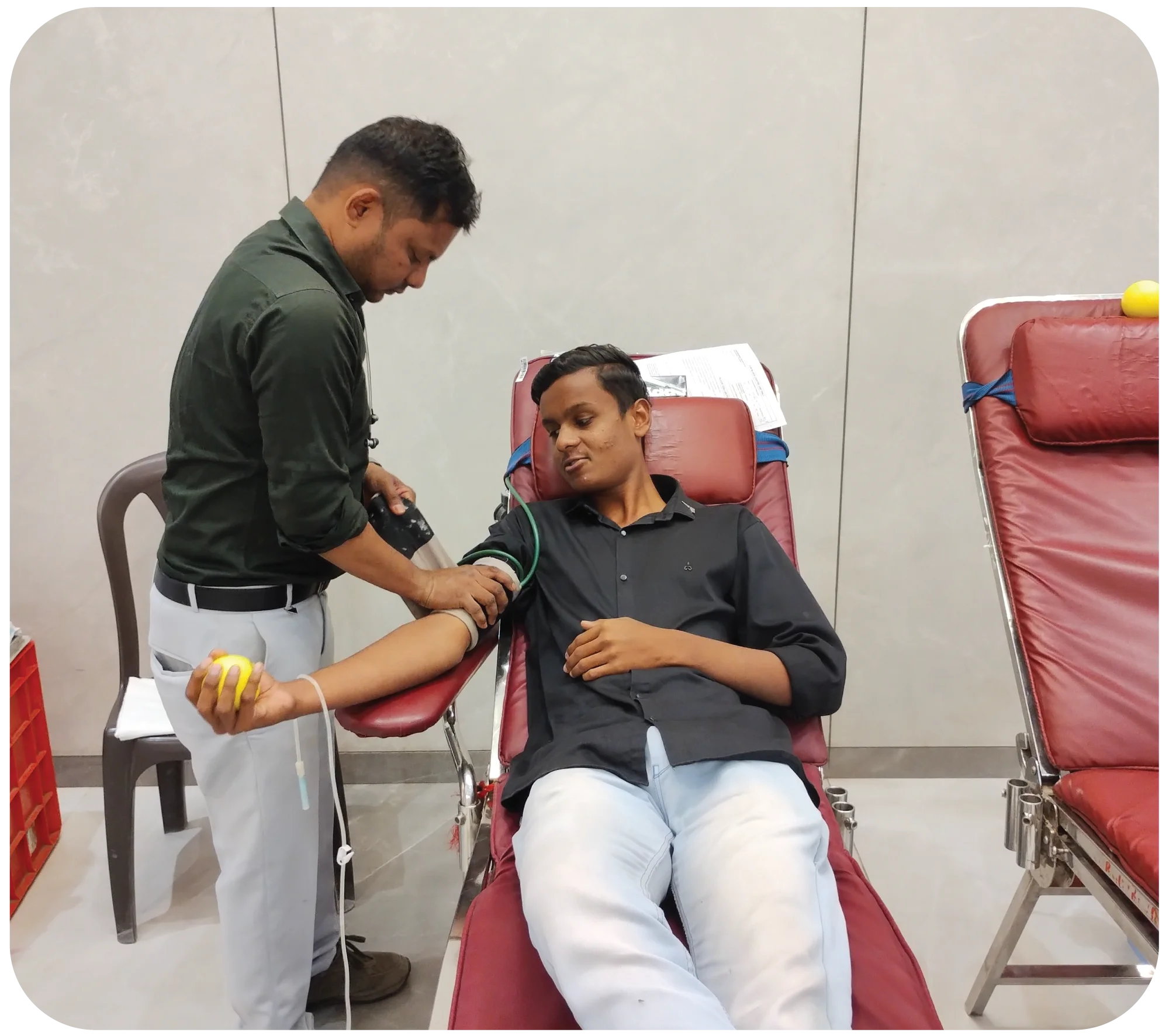 Two donors resting during blood donation while staff monitor them